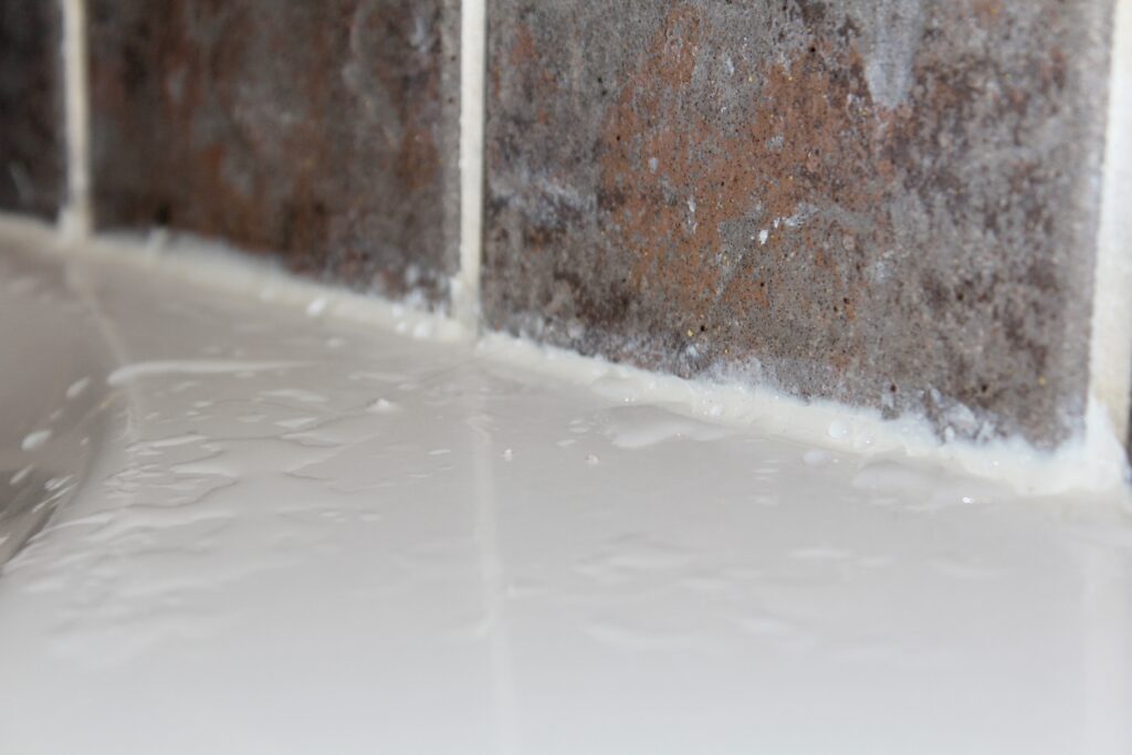 Water beads on the surface of new silicone bathroom caulking. 