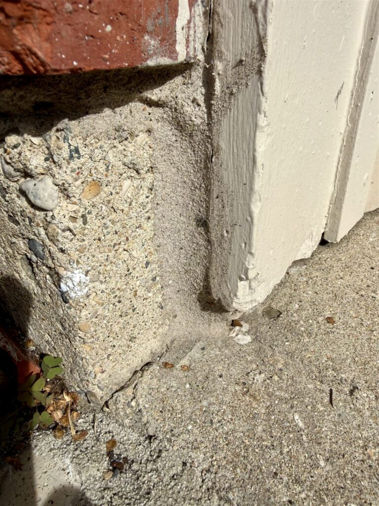 Gap at the base of garage door frame where it meets the driveway