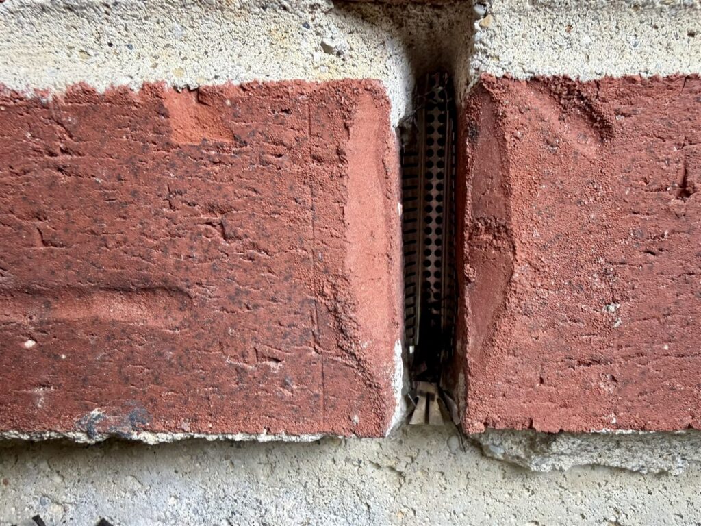 Metal mesh weep hole screen pressed into brick opening