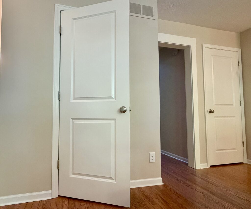 Three interior doors replaced in a 1980s home — two-panel prehung doors with brushed nickel hardware